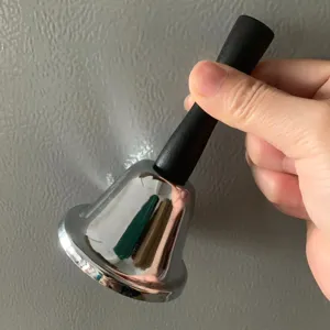 Detalle de campana de mano con cuerpo de metal plateado y mango negro para uso escolar.