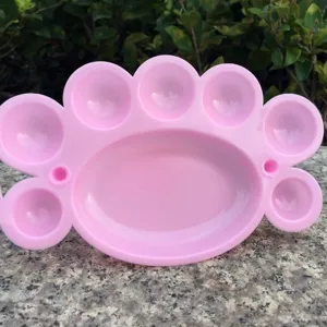 Tavolozza di colori in plastica rosa con scomparti multipli per pittura artistica fai da te.