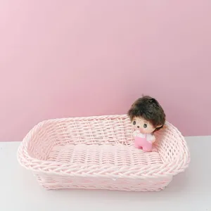 Vue détaillée du panier de rangement tissé en plastique rose sur un bureau propre.