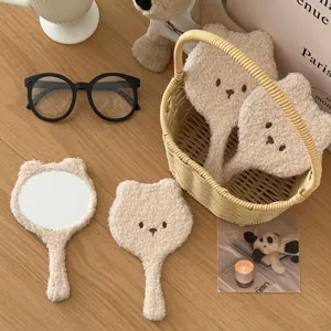 Close-up detail of cute plush bear handheld makeup mirror with soft fluffy fabric and embroidery.