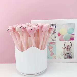 Gros plan détaillé de jolis stylos gel cochon rose rangés dans un pot à crayons blanc.