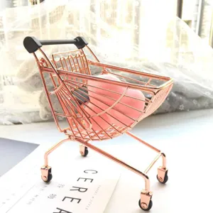 Mini metal shopping cart prop in rose gold with pink makeup sponge, perfect for desktop display.