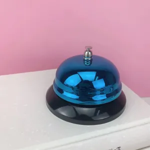 Primer plano de detalle de una campanilla de escritorio de metal azul con base negra juegos.