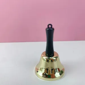 Detalle de campanilla de mano dorada, cuerpo de metal con mango negro para uso escolar.
