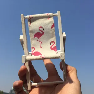 Mini holzstrandstuhl handyhalterung mit rosa flamingo muster im detailhaften anblick.