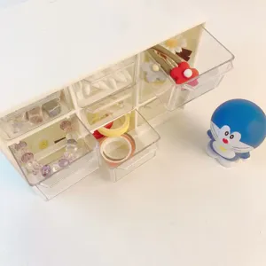 Clear acrylic desktop storage box detail view showing 9 drawers filled with cute small items.