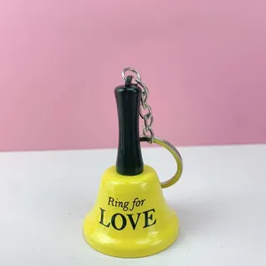 Primer plano detallado de un llavero de campana de llamada amarilla con mango negro.