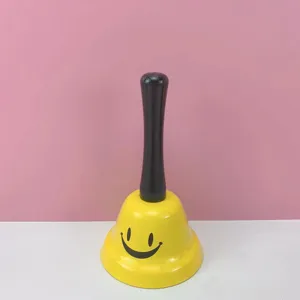 Campana de mano amarilla con mango negro, con un lindo diseño de cara sonriente negra.