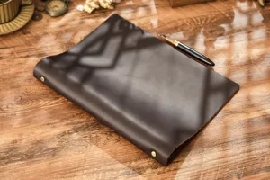 Primo piano di un quaderno raccoglitore in vera pelle marrone su un tavolo in legno.