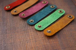 Organisateur de câble en cuir véritable, enrouleur coloré avec boutons-pression métalliques.