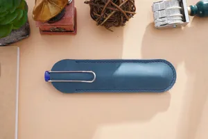 Nahaufnahme der blauen, handgemachten Lederstifthülle mit Metallclip auf holziger Oberfläche.