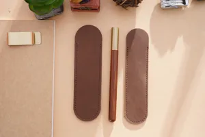 Nahaufnahme von vintage handgemachten Rindsleder Stifthüllen und Holzstift auf Tisch.