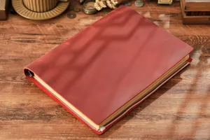 Primo piano dettagliato del quaderno con raccoglitore A4 in pelle vintage rossa su scrivania.