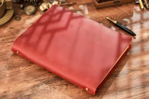 Primo piano dettagliato del taccuino vintage in vera pelle con raccoglitore su legno rustico.