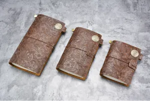 Gros plan de carnets de voyage en cuir gaufré vintage aux délicats motifs floraux.
