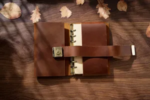 Handmade genuine leather A6 vintage notebook detail view with metal password lock on wooden table.