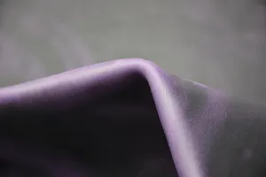Gedetailleerde close-up van paars leer met zachte gewaxte textuur en natuurlijke nerf.