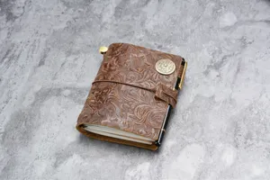 Carnet de voyage rétro en cuir véritable gaufré de fleurs avec détail de porte-stylo élégant.