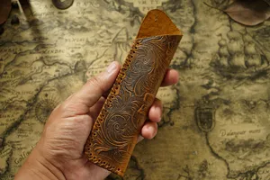 Handheld view showing embossed floral leather pen sleeve, vintage tooling style detail.
