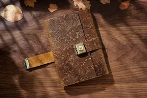Primer plano de cuaderno de cuero grabado vintage con motivo floral y cerradura de metal.