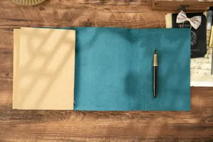 Detailansicht eines vintage türkisfarbenen Leder-Notizbuchs offen auf Holz mit Stift.