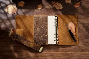 Primer plano detalle del cuaderno de cuero genuino grabado A5 sobre madera vintage.