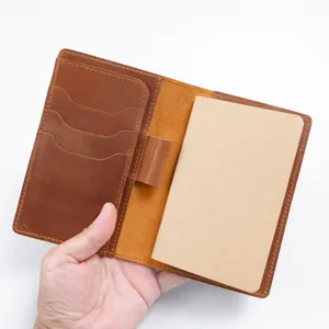 Vue detaillee de l'interieur du carnet en cuir marron avec fentes pour cartes et porte-stylo.