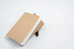 Vue de détail des carnets de notes en papier kraft empilés avec pages lignées et stylo.