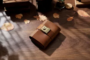 Close-up detail of vintage leather journal with brass combination lock on rustic wooden desk.