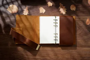 Close-up view of handmade genuine leather A6 loose-leaf binder notebook on wooden table.