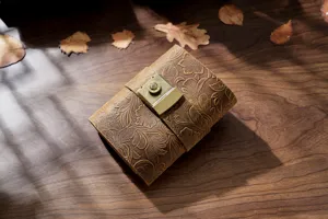 Vintage leather journal notebook detail view with embossed floral pattern and brass lock.
