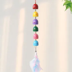 Colorful cartoon smiling face metal bell wind chime pendant detail shot, decorative craft item.