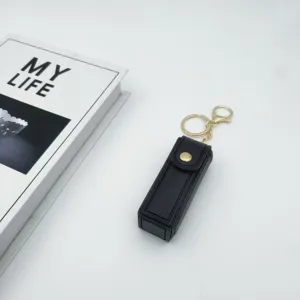 Black leather lipstick case keychain with gold hardware, elegant mini pouch for daily use.
