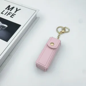 Pink leather lipstick case keychain with gold hardware, portable mini makeup bag charm.