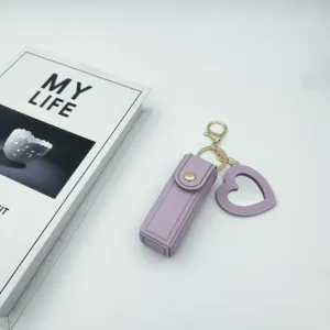 Purple leather lipstick case keychain with heart mirror pendant, chic bag charm accessory.