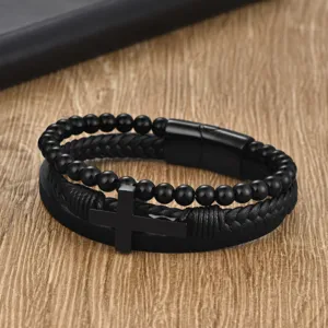 Macro view of black braided leather bracelet with stainless steel cross charm.