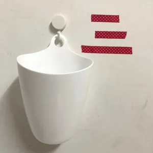 Vista dettagliata del cestino portaoggetti sospeso in plastica bianca con foro di montaggio.