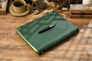 Vista dettagliata del taccuino ad anelli in pelle vintage verde scuro con una stilografica.