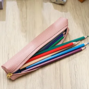Astuccio in pelle rosa con matite colorate su sfondo in legno, cancelleria carina.