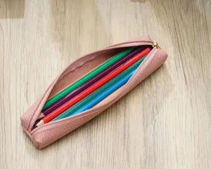 Primo piano dettagliato di un elegante astuccio in pelle rosa con matite colorate.