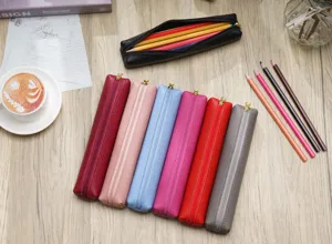 Vista dettagliata di astucci in pelle colorata su scrivania in legno con articoli di cancelleria.