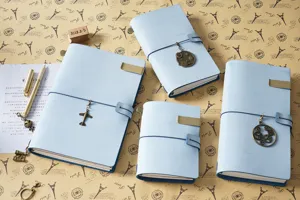Set di quaderni da viaggio in pelle con ciondoli metallici vintage e clip pratiche.