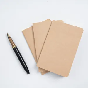 Set de carnets de notes rechargeables en papier kraft avec stylo plume sur fond blanc.