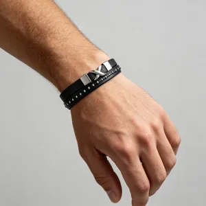 Detail van een meerlaagse zwarte lederen herenarmband met zilverkleurige metalen gesp en klinknagels.