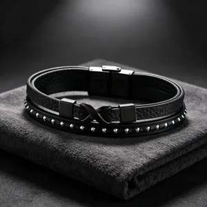 Close-up van heren armband van zwart leer met meerdere lagen en oneindigheidssymbool en studs.