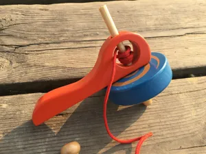 Juguete tradicional de madera con peonza de cuerda, diseño educativo clásico y colorido.