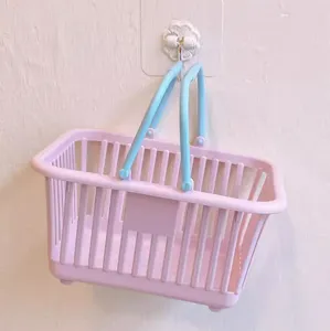 Detailed view of the cute pink plastic storage basket with blue handles for desktop organization.