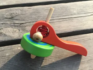 Juguete de peonza de madera tradicional para tirar con diseño colorido. Vista detallada.
