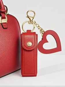Red leather lipstick case keychain with heart pendant and gold hardware for women bags.