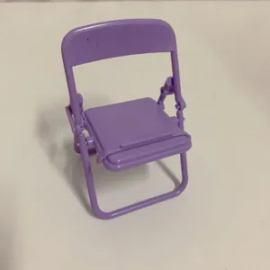 Close-up detail view of a purple mini folding chair phone stand and desktop decor.